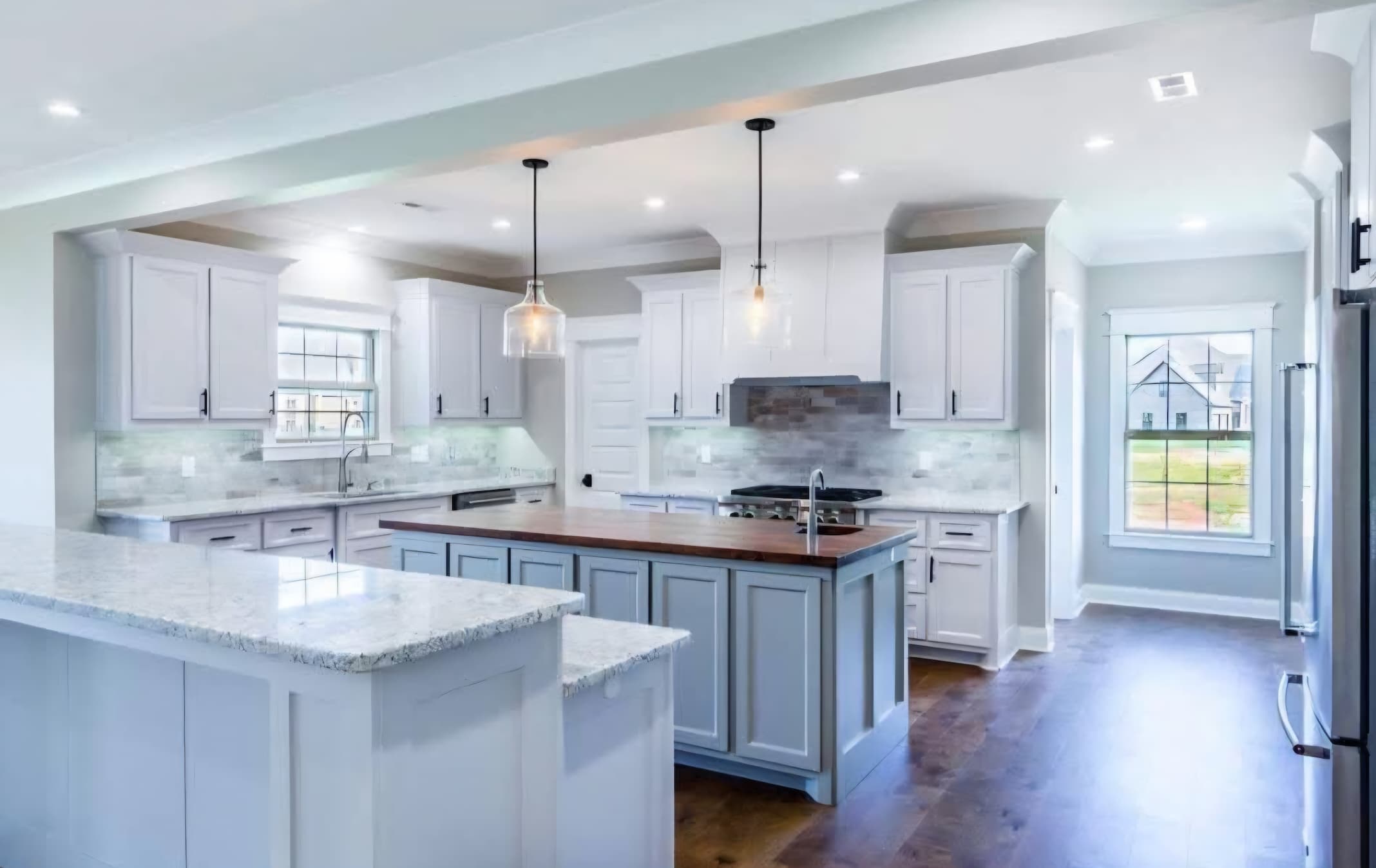 Large white kitchen with granite countertops and hardwood floors